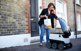 woman picking up food from a food delivery robot by starship technology